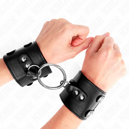 KINK - POLSO FISSO CON ANELLO E BORCHIE REGOLABILE NERO 17-22 CM X 6,5 CM - KINK COLLAR & GAG | Lingerie Harness Boutique